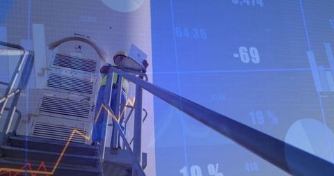 Engineer Holding Laptop With Financial Data Overlay in Industrial Setting