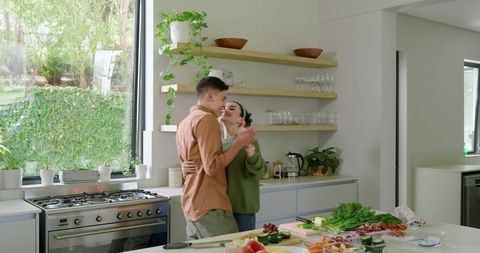 Happy Couple Dancing and Cooking in Modern Kitchen