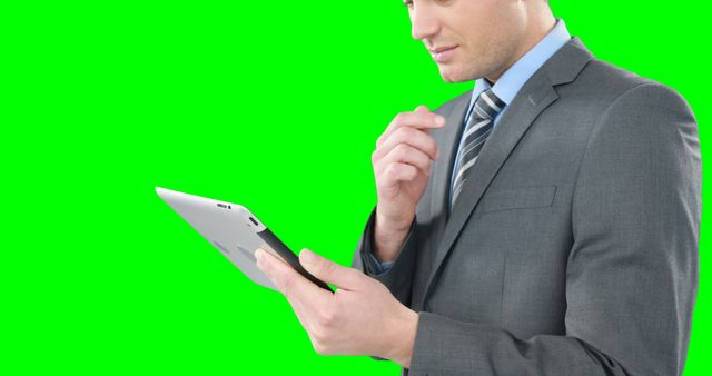 Businessman focusing on data analysis using tablet device against green screen background. Suitable for business, technology, digital work, corporate presentations, and marketing materials. Easy to edit, ideal for adding text or other visual elements.