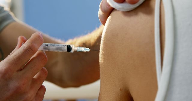 Close-up view of a healthcare professional administering a vaccine injection in a patient's arm. Ideal for content related to vaccination campaigns, public health awareness, medical care, and science.