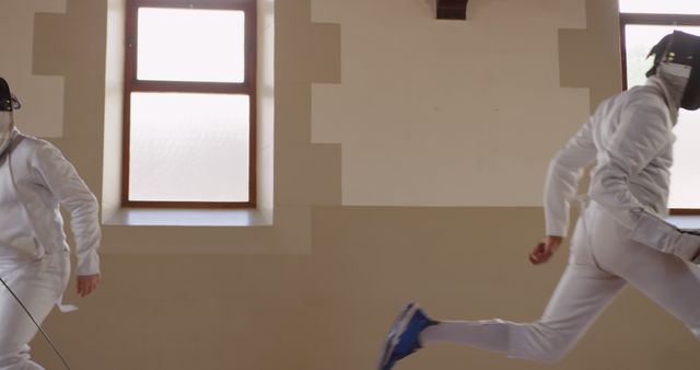 An athlete in uniform practicing fencing indoors near a window - Download Free Stock Images Pikwizard.com