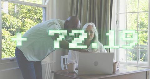 Helping senior woman using laptop with glowing digital analytics overlay +72.19