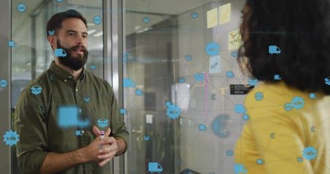 Collaborating on sales strategy on glass board with sticky notes, sketches and data icons