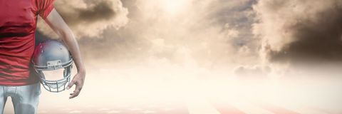 American Football Player Holding Helmet Under Dramatic Sky