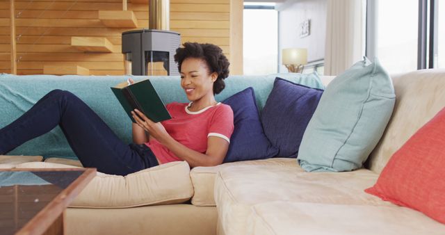 Image of african american woman reading book on sofa. Lifestyle and spending time at home concept.