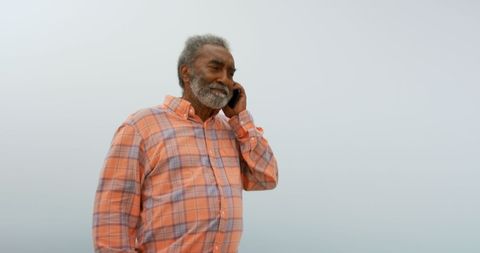 Senior African American Man Enjoys Phone Call at Beach