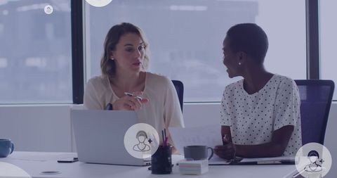 Diverse female colleagues collaborating on laptop in office