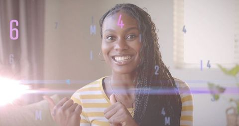 Cheerful Woman Giving Thumbs Up Surrounded by Digital Elements at Home