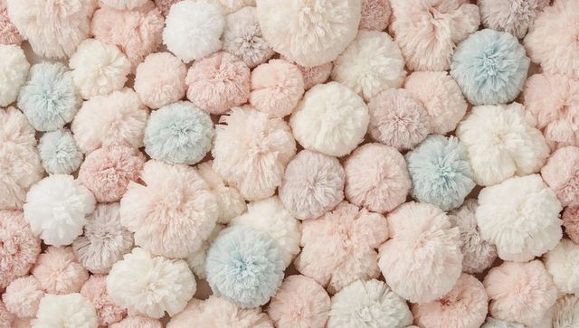 Pastel yarn pompoms creating soft textured background for nursery decor and crafts