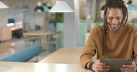 Smiling man using tablet in modern coworking space checking analytics boosting efficiency