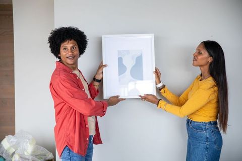 Couple aligning abstract art in modern inter