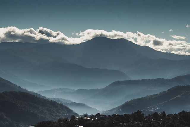 The image showcases a misty mountain range with numerous layers under a cloudy sky. Perfect for use in travel brochures, nature-themed blogs, wallpapers, or as background images for presentations focusing on natural beauty and outdoor exploration.