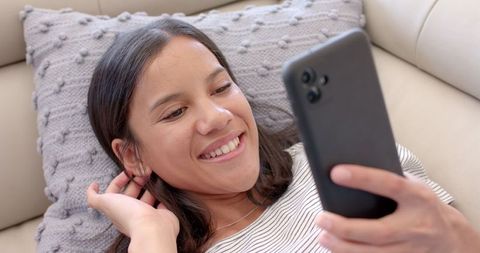 Happy Teen Girl Using Smartphone on Cozy Couch at Home