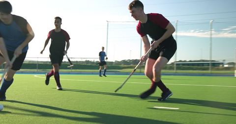 Athletes Competing in Field Hockey on Sunny Day
