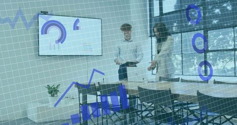 Colleagues reviewing business data and interactive charts in modern glass conference room