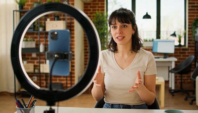 Creator Recording Livestream with Ring Light and Smartphone in Modern Brick Workspace