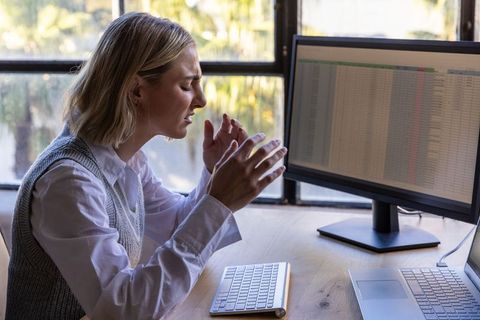 Stressed woman working on financial spreadsheet in bright home office