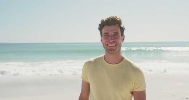 Young man smiling while enjoying a sunny day at the beach. Can be used for concepts of relaxation, vacation, summer enjoyment, lifestyle, and leisure activities. Suitable for advertisements, posters, travel blogs, and promotional materials related to travel and outdoor recreation.