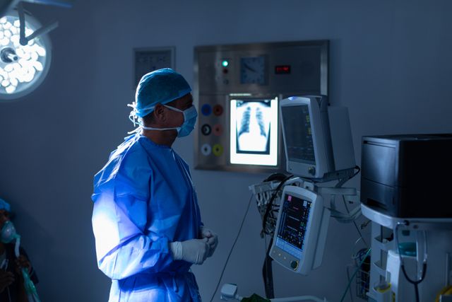 Side view of male surgeon looking at monitor in operating room at hospital