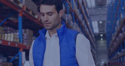 Warehouse worker checking inventory with handheld scanner in high-bay racking aisle