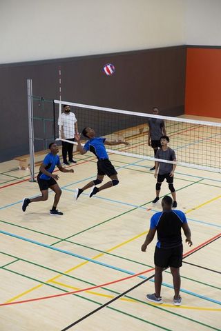 Indoor volleyball players leaping to spike ball during competitive match
