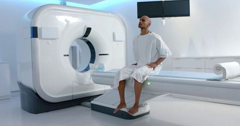 African american man sitting on ct scanner table preparing for diagnostic ct scan