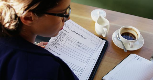 Businesswoman Reviewing Progress Report at Coffee Table - Download Free Stock Images Pikwizard.com