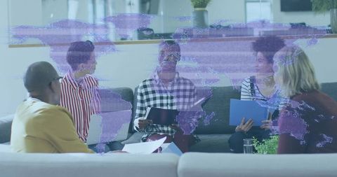 Diverse team collaborating in lounge with purple world map overlay for global planning