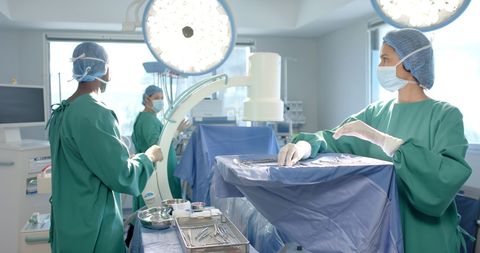 Diverse Surgical Team Prepares Operating Room with Medical Equipment