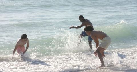 Friends Enjoying a Playful Day at the Beach in Ocean Waves - Download Free Stock Images Pikwizard.com