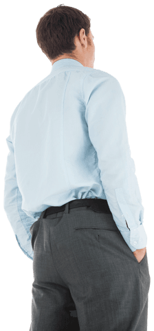 businessman is standing casually with hands in pockets, seen from the back wearing a light blue shirt and dark trousers, providing a professional yet relaxed imagery. ideal for use in business contexts, professional presentations, or workplace-related content to convey an atmosphere of calm and confidence in business environments.
