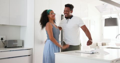 Happy Couple Embracing in Bright Kitchen While Planning