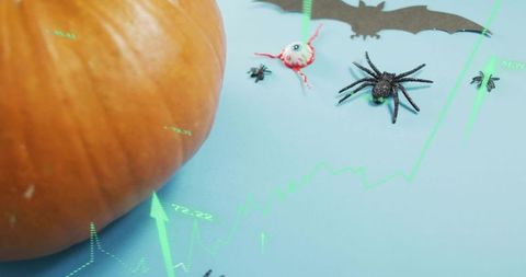 Displaying large pumpkin with Halloween props and neon market chart overlay on blue backdrop