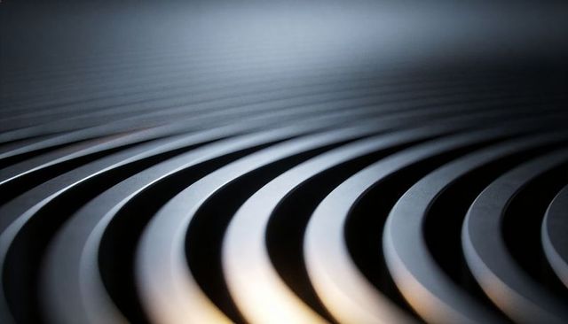 Abstract curved metal slats forming repeating diagonal rhythm with reflective highlights