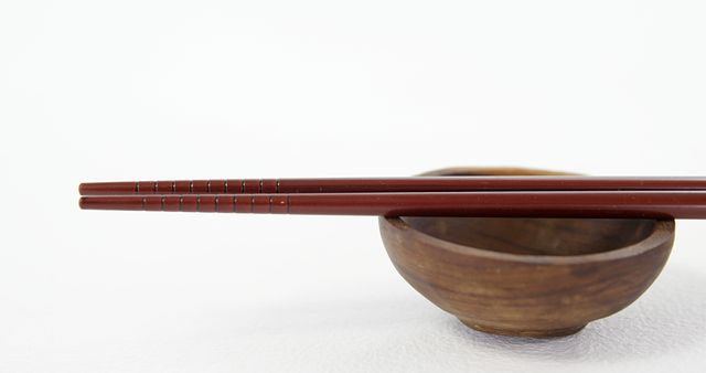 Close-up Red Chopsticks Resting on Wooden Bowl with White Background - Download Free Stock Images Pikwizard.com