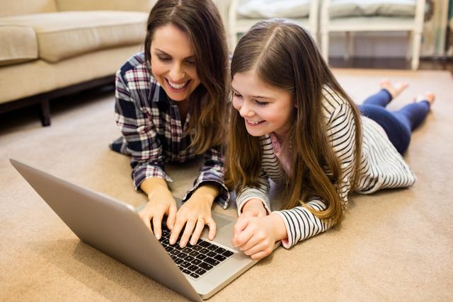 Happy mother and daughter using laptop in living room at home