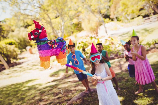 Little girl is going to broke the pinata for their birthday in a park