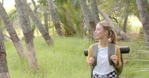 Young woman hiking through peaceful palm grove in sunshine