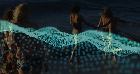 Friends walking into twilight surf with cyan digital wave double exposure