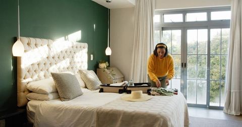 Woman Packing Suitcase in Cozy Bedroom with Natural Light