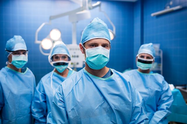Group of surgeons standing confidently in an operating room setting. Ideal for healthcare promotions, medical articles, and educational materials showcasing medical professionals at work. Useful for illustrating teamwork and the medical environment.