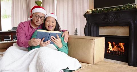 Happy Couple Reading by Fireplace During Christmas Season