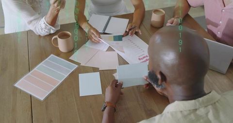 Creative team reviewing color swatches and brand materials around wooden meeting table