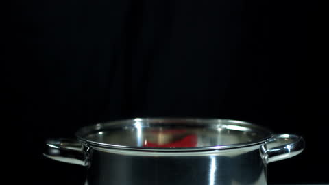 Red Chili Pepper Falling into Stainless Steel Pot in Slow Motion