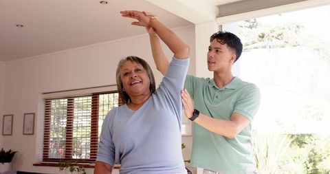 Young Physiotherapist Assisting Senior Woman with Arm Exercises