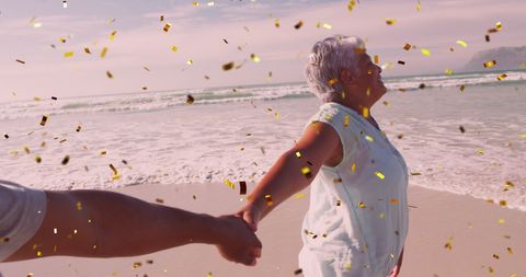 Elderly couple celebrating joy at beach with confetti