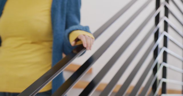 Person in Yellow Sweater and Blue Coat Holding Handrail on Modern Staircase - Download Free Stock Images Pikwizard.com