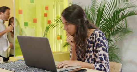 Focused Businesswoman Using Laptop in Creative Workspace