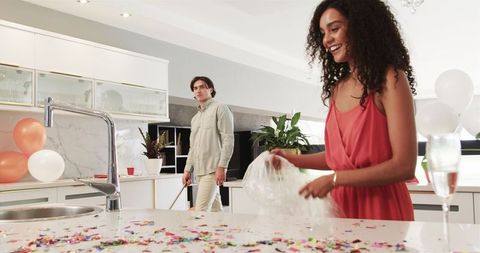 Couple Cleaning Confetti After Celebration in Modern Kitchen