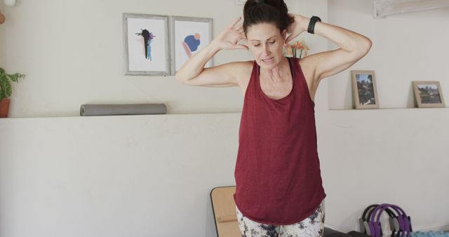 Middle-aged woman engaged in exercise routine indoors wearing a casual outfit. This image is suitable for use in articles, blogs, or advertisements related to home workouts, healthy lifestyles, fitness routines, and the importance of physical activity for overall well-being.